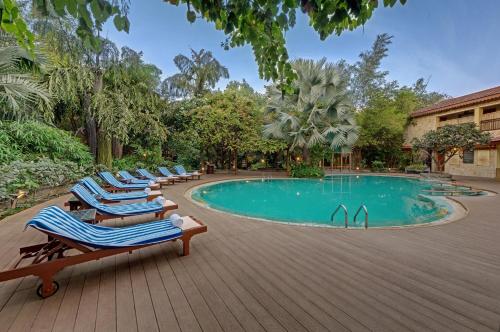 萨三吉尔The Fern Gir Forest Resort, Sasan Gir - A Fern Crown Collection Resort的游泳池旁的一排躺椅