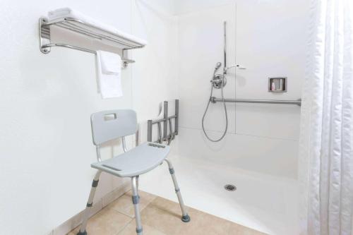 萨克拉门托萨克拉门托速8酒店的浴室内带椅子的白色淋浴