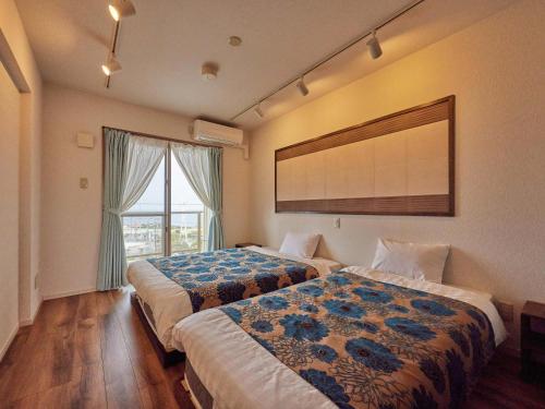 本部Yukurina Resort Okinawa的酒店客房设有两张床和窗户。