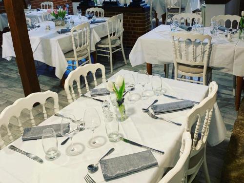 圣奥梅尔昂绍塞Logis - Hôtel & Restaurant Moulin Des Forges的一组桌子,上面有白色的桌布和眼镜