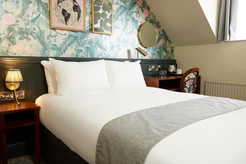 NarboroughNarborough Arms的卧室配有白色大床,拥有蓝色和绿色的壁纸