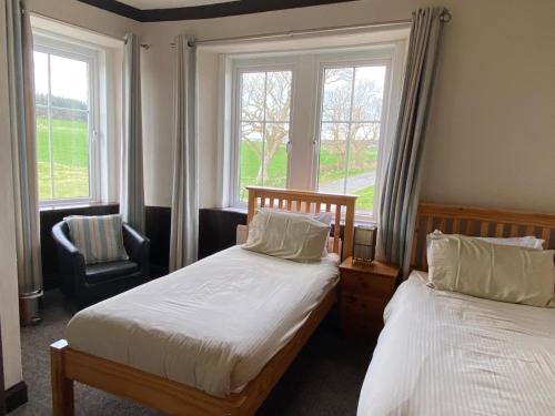 KilchattanKingarth Hotel的一间卧室设有两张床、一把椅子和窗户。