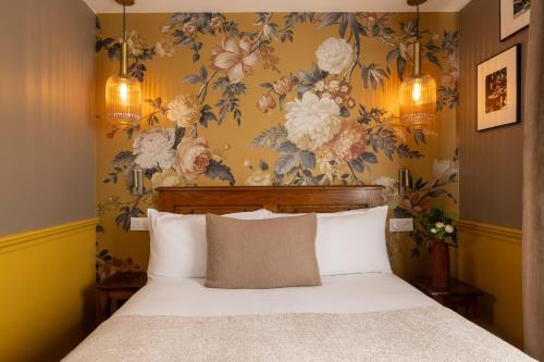 巴黎迎宾酒店的一间卧室配有一张带花卉壁纸的床