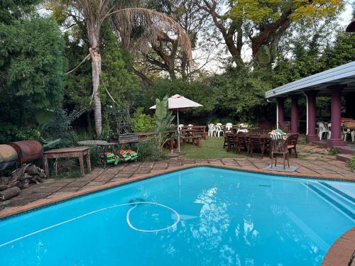 比勒陀利亚Pebble Fountain Guesthouse的庭院内的游泳池,配有桌椅