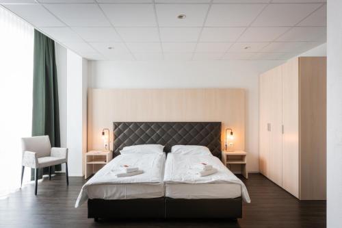贝尔普Los Lorentes Aparthotel Bern Airport的一间卧室配有一张大床和两条白色毛巾