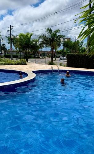 马塞约Casa Aeroporto Maceió Palmeiras的两人在蓝色的大型游泳池游泳