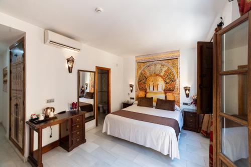 科尔多瓦Hotel Casa Museo de la Mezquita的一间卧室配有一张床、一张书桌和一面镜子