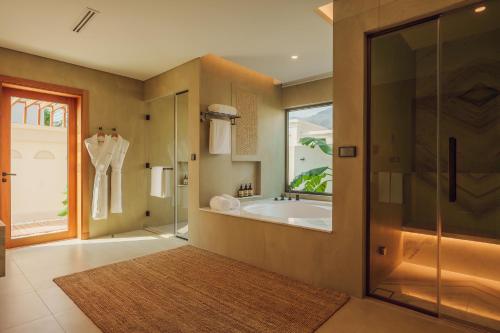 艾阿卡Naama Beach Villas & Spa的带浴缸和玻璃淋浴间的浴室。