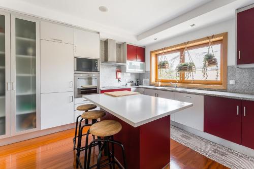 加亚新城GuestReady - Sophistication and refinement的厨房配有红色和白色的橱柜和凳子