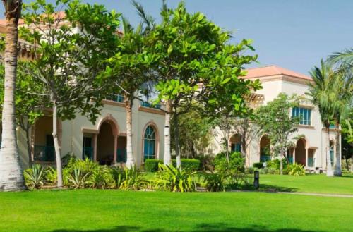 阿布扎比Al Raha Beach Hotel - Superior Room SGL - UAE的绿色草和棕榈树的房子