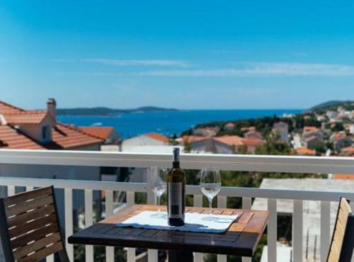 赫瓦尔Apartments Trogrlić的阳台上的桌子上摆放着一瓶葡萄酒