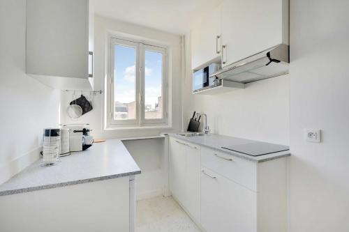 巴黎Bel Appartement - 3P Proche Champs de Mars的白色的厨房配有白色橱柜和窗户
