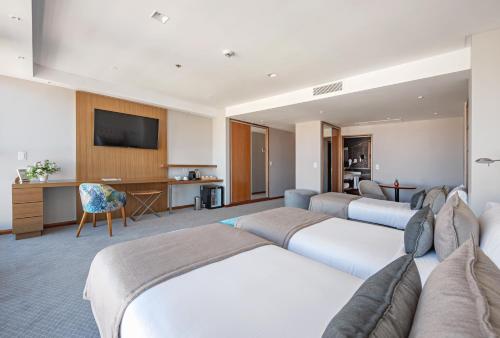 马德普拉塔HOTEL KONKE MAR DEL PLATA的一间酒店客房,设有三张床和一台平面电视