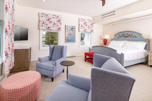麦基诺岛The Inn at Stonecliffe的一间卧室配有一张床铺和椅子以及一台电视。