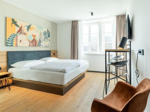 阿尔布斯塔特B&B HOTEL Albstadt-Hbf的配有一张床和一把椅子的酒店客房