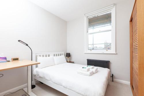 布莱顿霍夫GuestReady - Espaço maravilhoso em Brighton e Hove的一间卧室配有一张床、一张书桌和一个窗户。