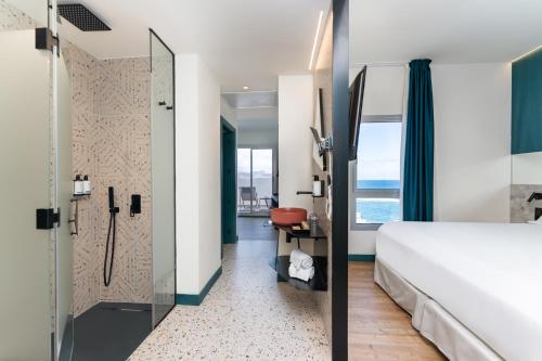 大加那利岛拉斯帕尔马斯Occidental Las Canteras的酒店客房配有一张床和淋浴