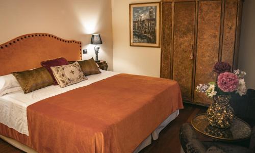威尼斯拉卡尔西纳酒店的一间卧室,配有一张床,桌子上放着花瓶