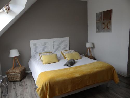 Ganzevillegite la fécampoise près de Fécamp的一间卧室配有一张带黄床单和两盏灯的床。