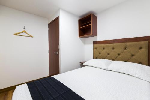 波哥大Hotel Casa Botero 102的卧室配有白色床和棕色床头板