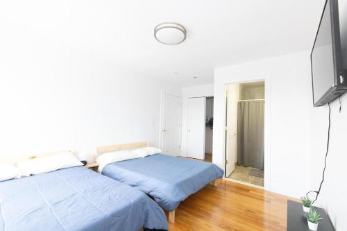 联城Pristine 2-Bed Apt with Skyline Views - mins to NYC的配有白色墙壁和木地板的客房内的两张床