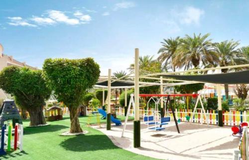 阿布扎比Al Raha Beach Hotel - Superior Room DBL - UAE的公园内设有一个种有树木和秋千的游乐场