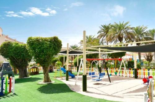 阿布扎比Al Raha Beach Hotel - Gulf View Room SGL - UAE的公园内带秋千和树木的游乐场