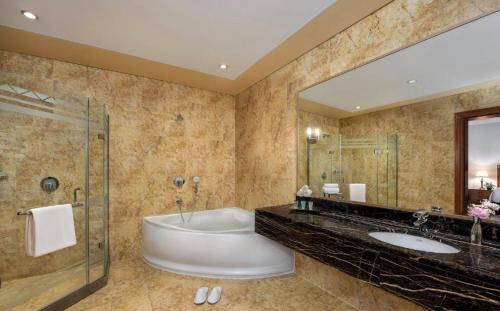 阿布扎比Al Raha Beach Hotel - Gulf View Room SGL - UAE的带浴缸、两个盥洗盆和淋浴的浴室。