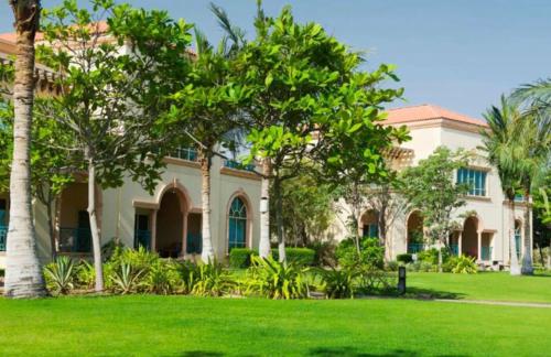 阿布扎比Al Raha Beach Hotel - Gulf View Room SGL - UAE的庭院里棕榈树的房子