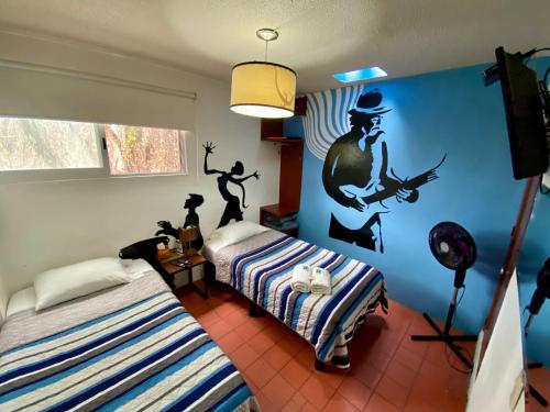 瓜达拉哈拉查普尔特佩克旅舍的一间卧室配有两张床,墙上挂着一具枪的男人壁画