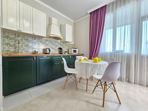 阿拉木图ЖК ATREA 2 room Apartment的厨房配有绿色橱柜和白色的桌椅