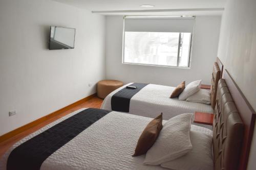 波哥大Hotel Casa Botero 201的一间卧室设有两张床和窗户。