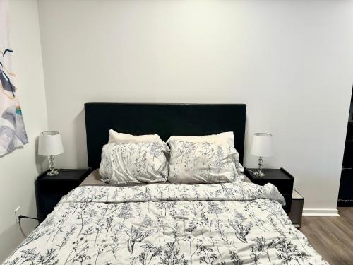 蒙特利尔Beautiful Luxury Shared Home in Montreal的一间卧室配有一张带黑色床头板的床和两盏灯。