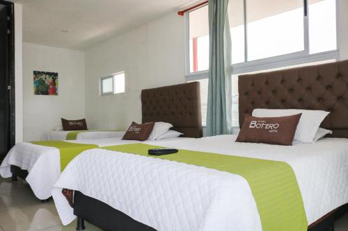波哥大Hotel Casa Botero 303的客房内的两张床,配有白色和绿色床单