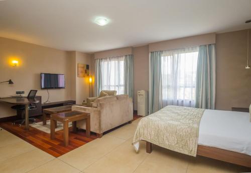 内罗毕Taarifa Suites by Dunhill Serviced Apartments的酒店客房配有一张床、一张沙发和一张书桌。