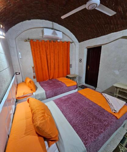 阿斯旺ABU Guest House的橙色窗帘间内的两张床