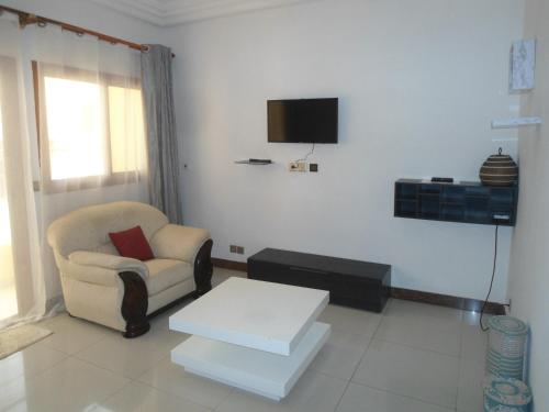 达喀尔Daaru Jamm的客厅配有椅子和墙上的电视