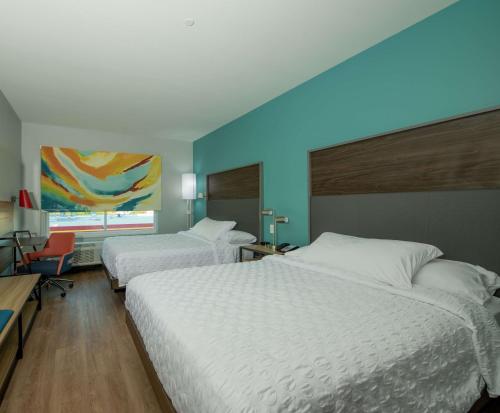 本殖民地Tru By Hilton The Colony的一间卧室设有两张床和蓝色的墙壁