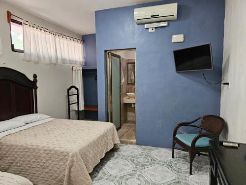 巴利亚多利德Casa Xu´unan的一间卧室设有一张床,蓝色的墙壁上设有一台电视机