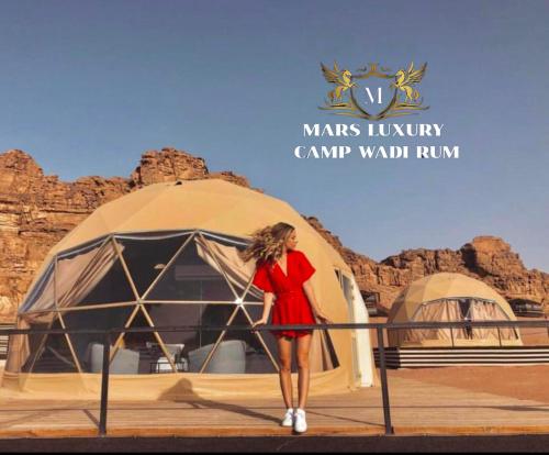 瓦迪拉姆MARS lUXURY CAMP WADI RUM的身着红色衣服的女人站在帐篷前