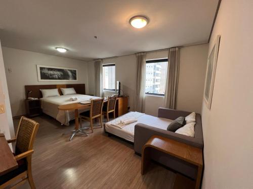 圣保罗Suíte 5 estrelas Hotel Moema Times Square 1412的酒店客房带两张床、一张桌子和一张沙发