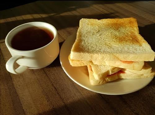 武吉丁宜Tapian Asri Camp的夹三明治和咖啡的盘子