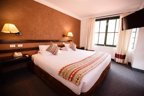 库斯科Hotel Raymi的一间设有大床和窗户的酒店客房