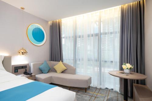 惠州铂顿国际公寓酒店(惠州经济学院店)的酒店客房设有床、沙发和窗户。