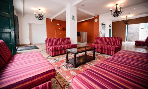 库斯科Hotel Raymi的一间设有红色椅子和桌子的等候室