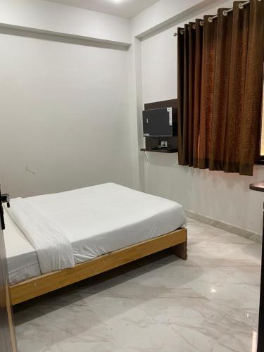 瓜廖尔AMALTAAS HOMESTAY的卧室配有一张床,墙上配有电视。
