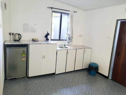 努格古达宾至如归度假屋的厨房配有白色橱柜、水槽和窗户。