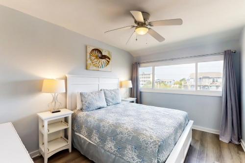 翡翠岛Oceanfront Oasis的一间卧室配有一张带吊扇和窗户的床。