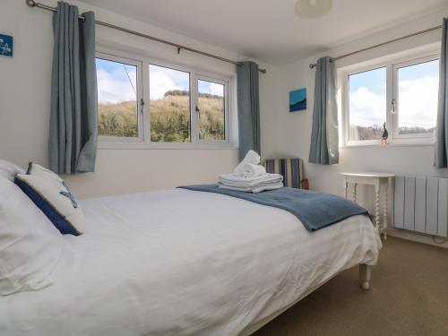 PorthallowCockle Island Cott的卧室配有一张白色大床和两个窗户
