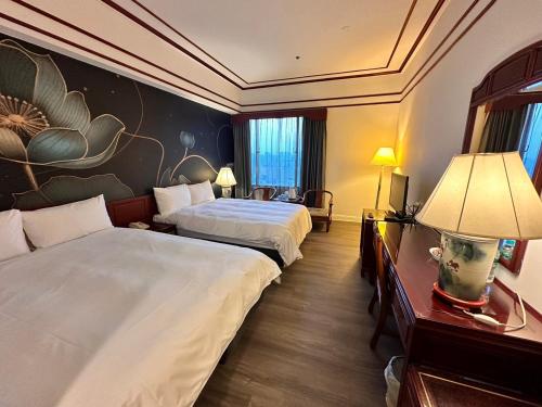 台中市T Hotel的酒店客房设有两张床,墙上挂有绘画作品